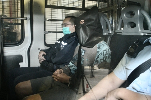 被告今身穿褐色上衣及戴黑框眼镜，被警员押至东区裁判法院提堂。